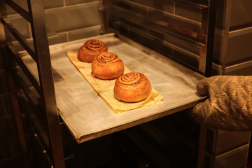 Woman holding tray with buns in bakery