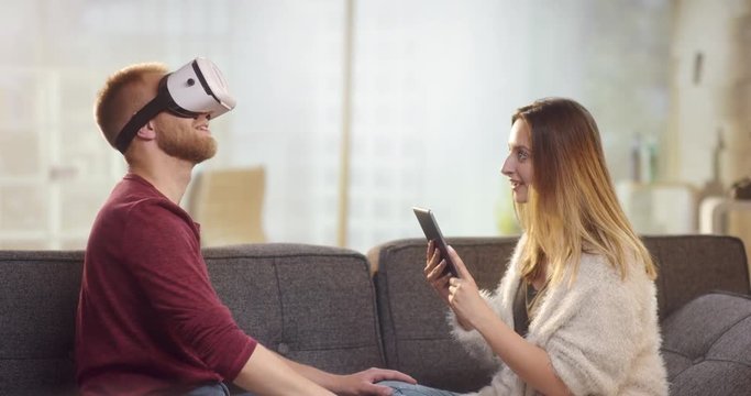 Young sweet couple on couch playing with VR and having fun