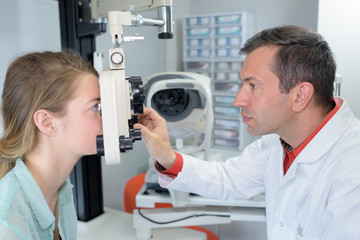 Naklejka na ściany i meble Optometrist aligning equipment to patient's face