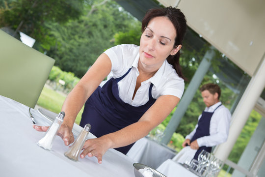Waitress putting salt and pepper onto table