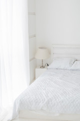 Abstract white room interior with white bed, lamp and window