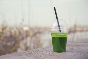 Cup of green fresh vegetable smoothie on street