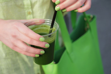 Woman holding cup of green smoothie, closeup