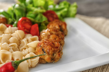 Plate with turkey meatballs, pasta and vegetables on table, closeup