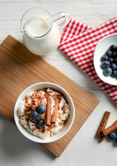 Delicious rice pudding with cinnamon and blueberries in bowl on kitchen table