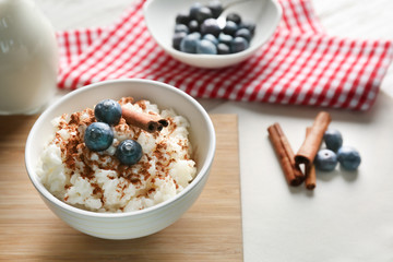 Delicious rice pudding with cinnamon and blueberries in bowl on kitchen table