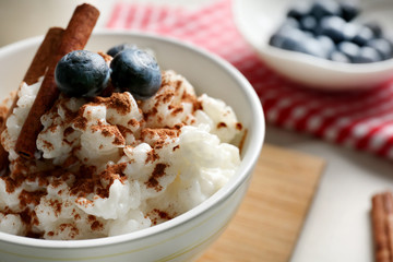 Delicious rice pudding with cinnamon and blueberries in bowl on kitchen table