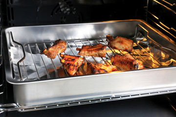 Baking tray with delicious pork ribs in oven, closeup