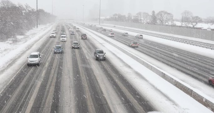 Cars driving in traffic on a snow covered road during a winter blizzard