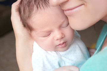 Happy young woman holding her newborn baby boy, closeup
