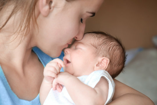 Happy young woman kissing her newborn baby boy, closeup