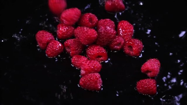 Fresh juicy raspberries falling in the water in slow motion. Shooting with high-speed camera
