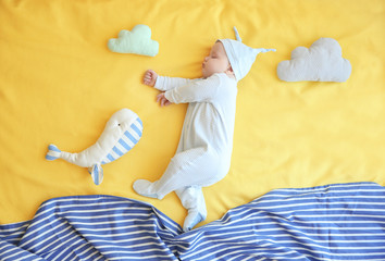 Cute little baby with toys sleeping on bed at home