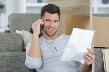 smiling man using mobile phone near paper at home