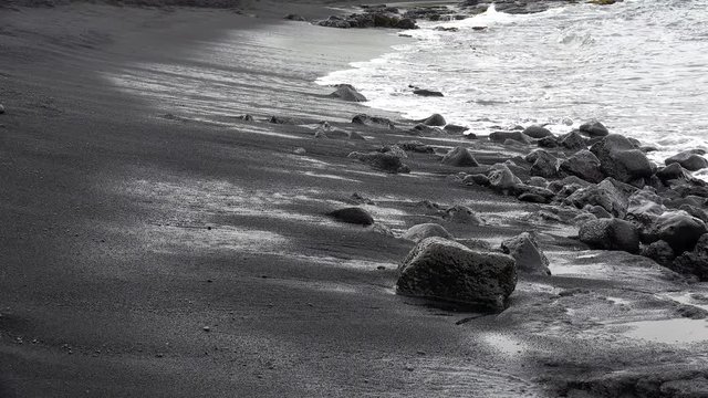 Surf wave on black sand at the Punaluu Beach. Big Island, Hawaii, USA