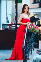 Beautiful brunette young woman wearing red dress,walking on the street.Fashion photo