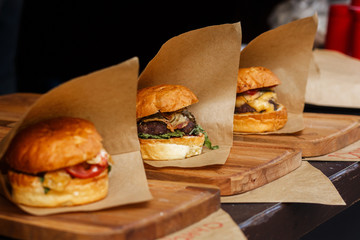 delicious burgers on craft paper, serving bbq at open grill, outdoor kitchen. food festival in...