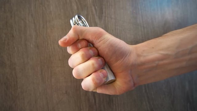 young athlete compresses and decompresses silver metallic manual expander.