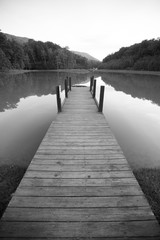 Naklejka premium Zadokuj na jeziorze z odblaskową powierzchnią i dramatyczną perspektywą