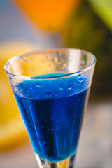 Blue exotic drink on the beach with palms in background