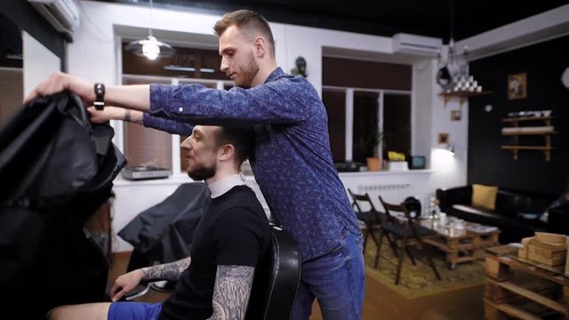 Side view of master combing hair to male customer in barber shop