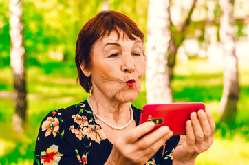 Grandmother and phone. Kiss on the camera.