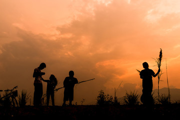 Group of happy children playing on meadow at sunset, silhouette