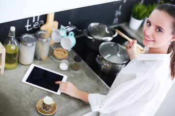 Young woman standing by the stove in the kitchen . Woman cooking in the kitchen.