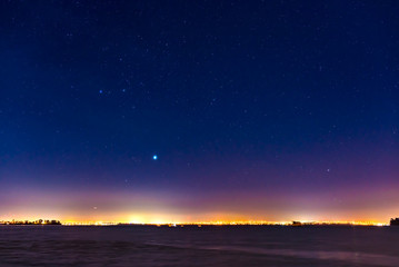 mist and a starry sky above the lights of a city skyline on the waterfront in Auckland, New Zealand