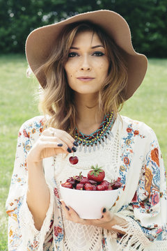 Stylish woman in a hat with a bowl of cherries