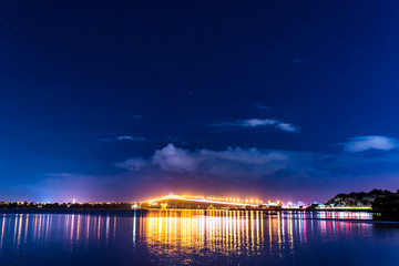 cars in motion on a lighted bridge over the sea with a starry sky, boats in Auckland, New Zealand