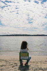 Child on chair beach cloudy sky 