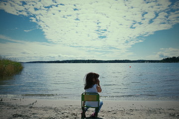 Child on a chair on beach cloudy sky 