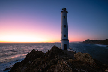 Fototapeta na wymiar Lighthouse at sunset in rocky coast in galicia, spain