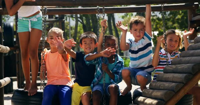 Portrait of happy African American boy schoolkids waving hands in playground