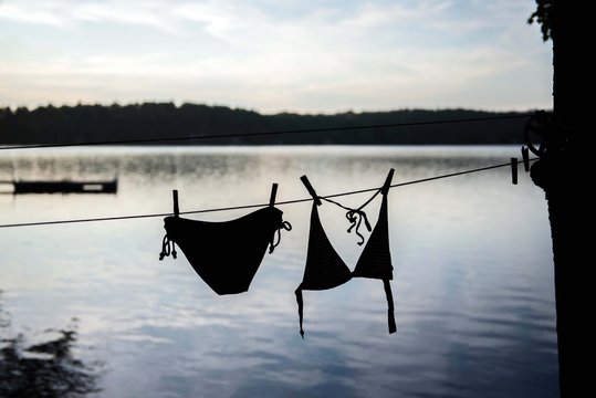 At the edge of a lake, a woman's bathing suit hangs on the clothesline to dry 