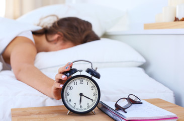 A young woman putting her alarm clock off in the morning.