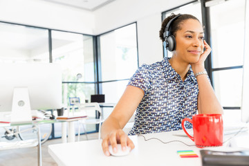 Portrait of smiling afro-american office worker sitting in offfice with headphones