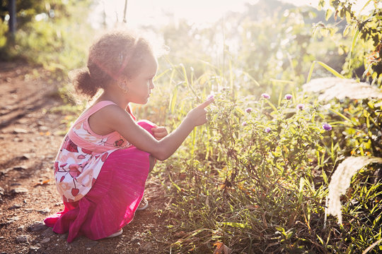 Portrait of a young girl admiring a flower on a warm summer day