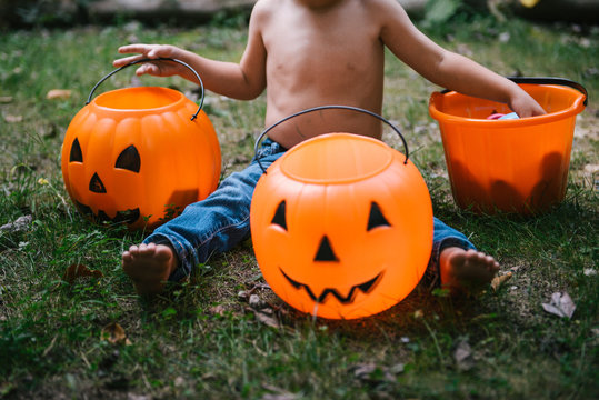toddler reaches into halloween pumpkin decorations