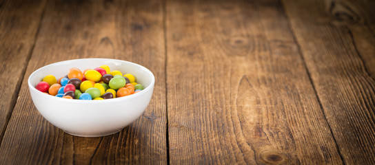 Portion of Cocolate coated Peanuts on wooden background (selective focus)