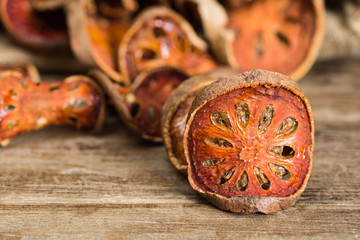 close up dried slice bael fruit on wooden table, blurred background