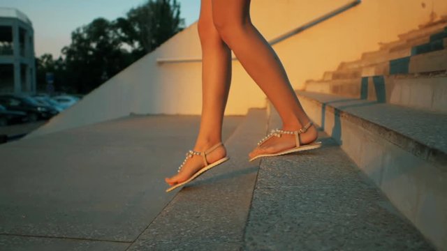 Woman legs in fashionable sandals going down the stairs outrdoor. Slow motion. Summertime