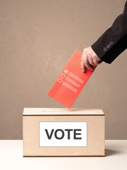 Close up of male hand putting vote into a ballot box