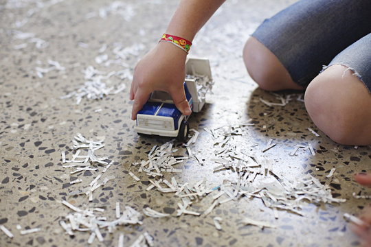 Close up of young boy playing with toy truck and pretend snow / shredded paper 