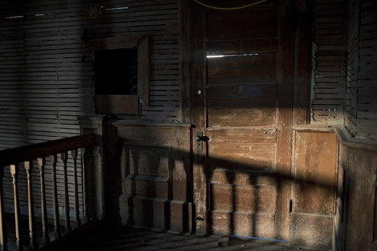 An old, splintered door in afternoon shadows at an abandoned school
