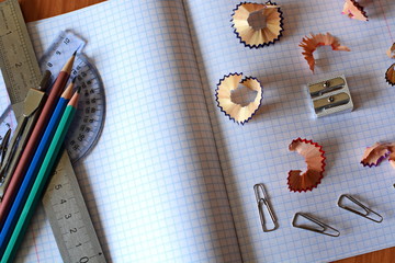cell school notebook on which there are sharp colored pencils, pencil sharpener, compasses, ruler,...
