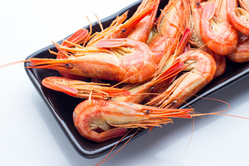 Shrimp on a black plate on a white background closeup.