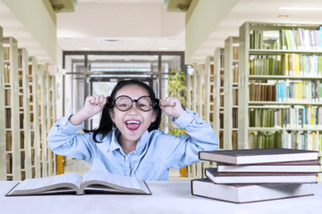 Cheerful girl celebrating her success in library