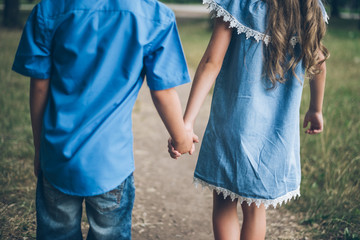 A little boy and girl walking together and holding each other hands - Powered by Adobe